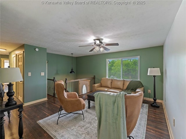 living room with baseboards, a ceiling fan, wood finished floors, and a textured ceiling