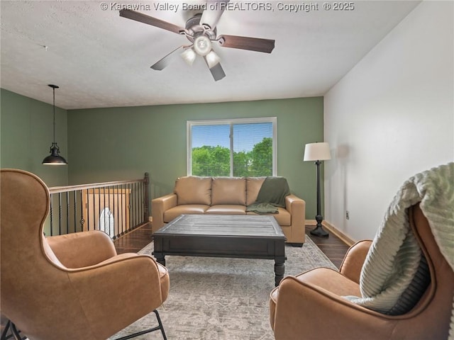 living area featuring wood finished floors, a ceiling fan, and baseboards