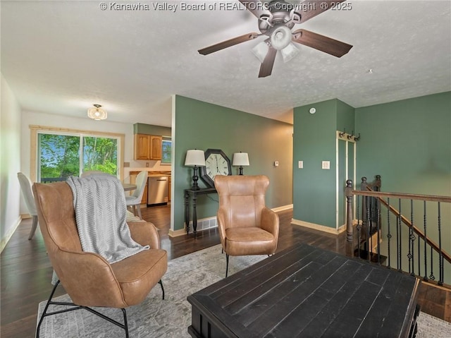 living room with wood finished floors, baseboards, ceiling fan, and a textured ceiling