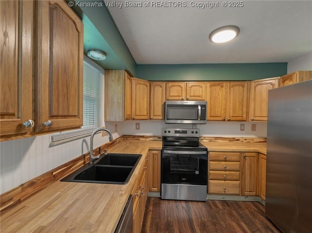 kitchen with stainless steel appliances, wooden counters, a sink, and dark wood-type flooring