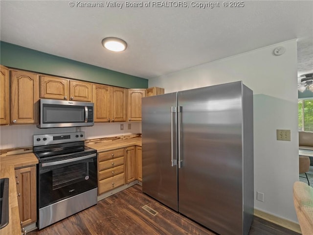 kitchen featuring appliances with stainless steel finishes, dark wood-style floors, and butcher block counters