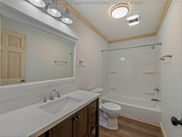bathroom with wood finished floors, toilet, ornamental molding, vanity, and washtub / shower combination