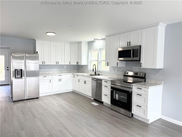 202 Josephine Ave, Madison, WV 25130 - kitchen featuring stainless steel appliances, a sink, light wood-style floors, and white cabinets