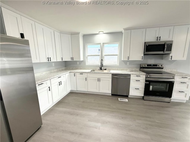 202 Josephine Ave, Madison, WV 25130 - kitchen with stainless steel appliances, a sink, white cabinetry, and light wood finished floors