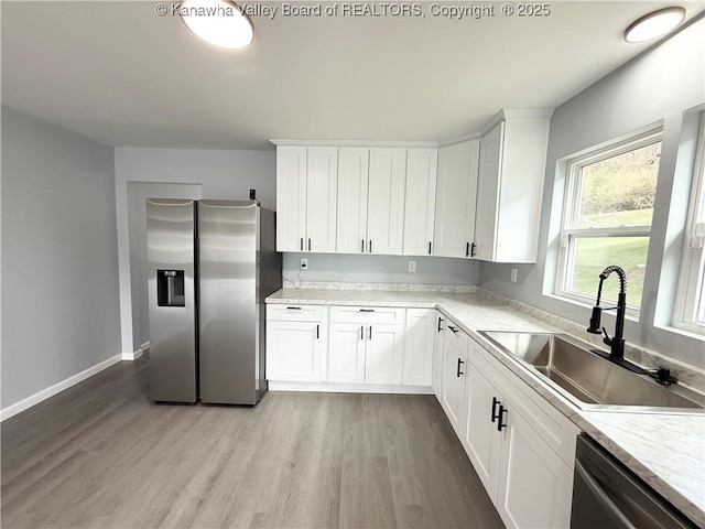 202 Josephine Ave, Madison, WV 25130 - kitchen with stainless steel appliances, a sink, light wood-style floors, light countertops, and white cabinetry