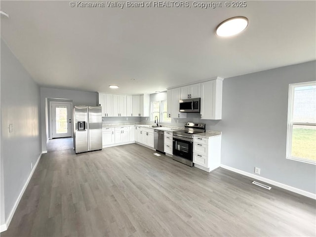 202 Josephine Ave, Madison, WV 25130 - kitchen featuring appliances with stainless steel finishes, a sink, baseboards, light countertops, and light wood-style flooring