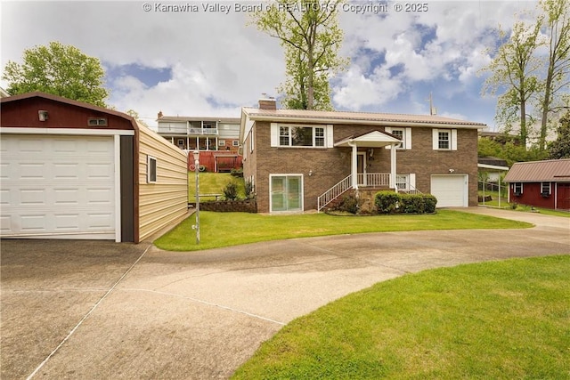 raised ranch with a garage, a chimney, concrete driveway, brick siding, and a front lawn