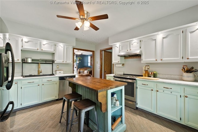 3589 Mount Union Rd, Fraziers Bottom, WV 25082 - kitchen with appliances with stainless steel finishes, butcher block countertops, under cabinet range hood, a ceiling fan, and wood finished floors