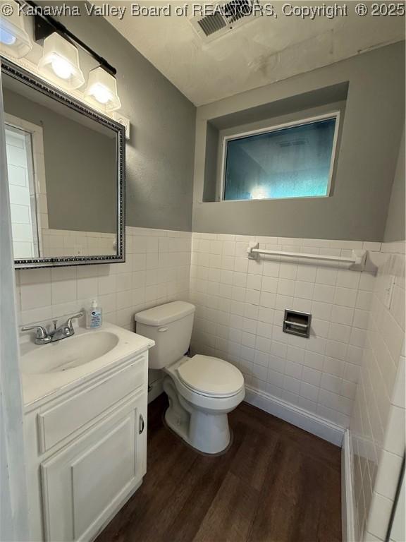 2 Stephanie Ln, Saint Albans, WV 25177 - half bathroom with tile walls, wood finished floors, toilet, a wainscoted wall, and vanity