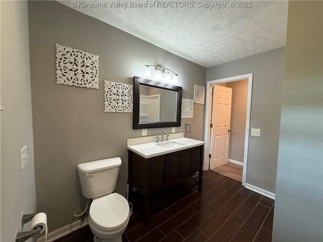 2 Stephanie Ln, Saint Albans, WV 25177 - bathroom with baseboards, wood finished floors, toilet, a textured ceiling, and vanity