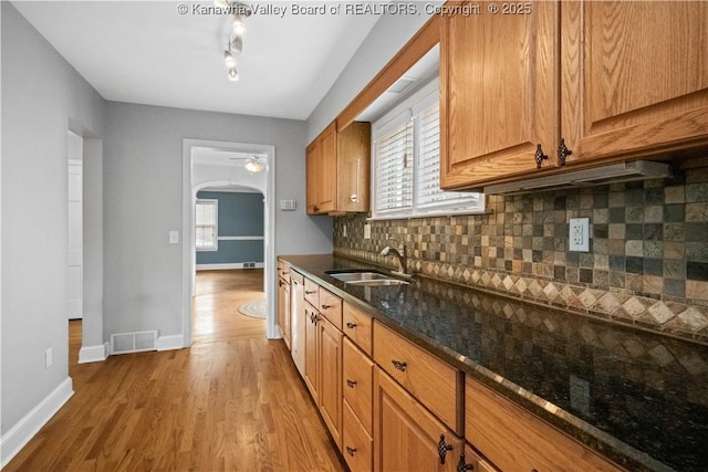 102 49th St SE, Charleston, WV 25304 - kitchen with a sink, light wood-style floors, dark stone countertops, baseboards, and decorative backsplash