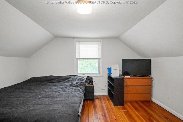 bedroom featuring wood finished floors, vaulted ceiling, and baseboards