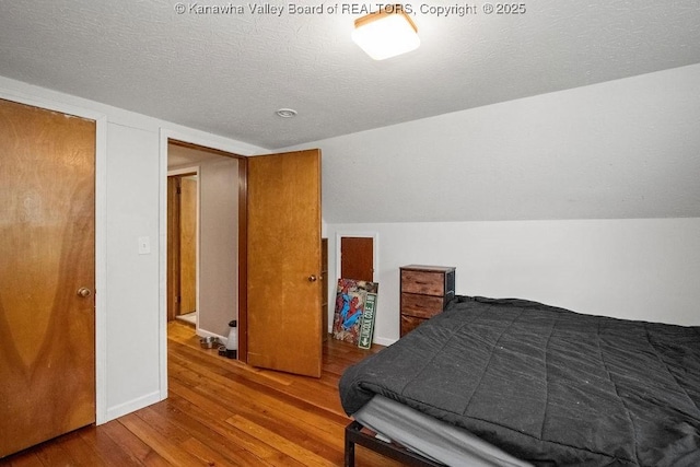 bedroom featuring wood finished floors, a textured ceiling, and baseboards