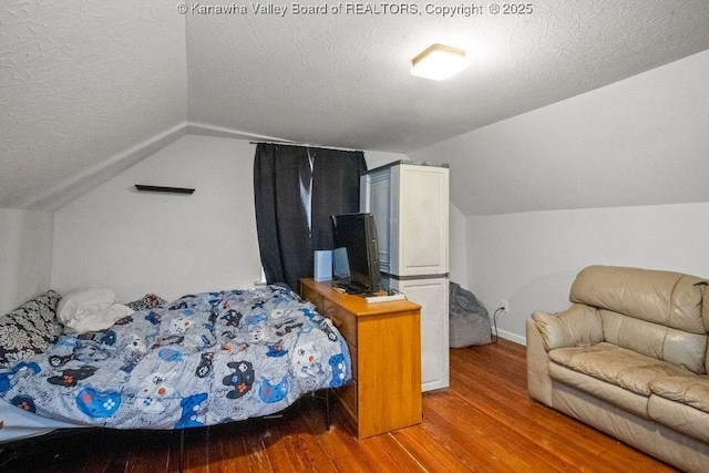 bedroom featuring lofted ceiling, wood finished floors, a textured ceiling, and baseboards