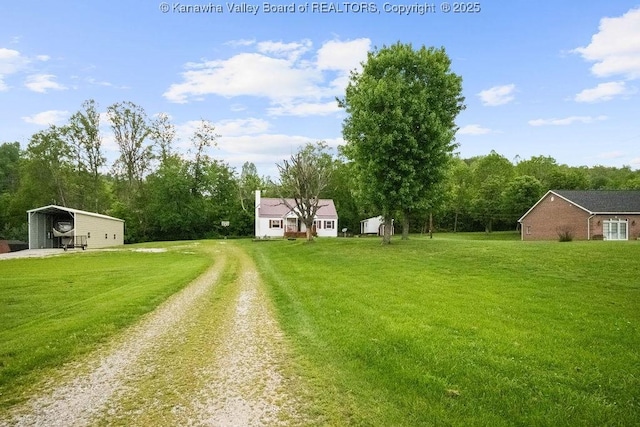 view of grassy yard featuring driveway and a carport