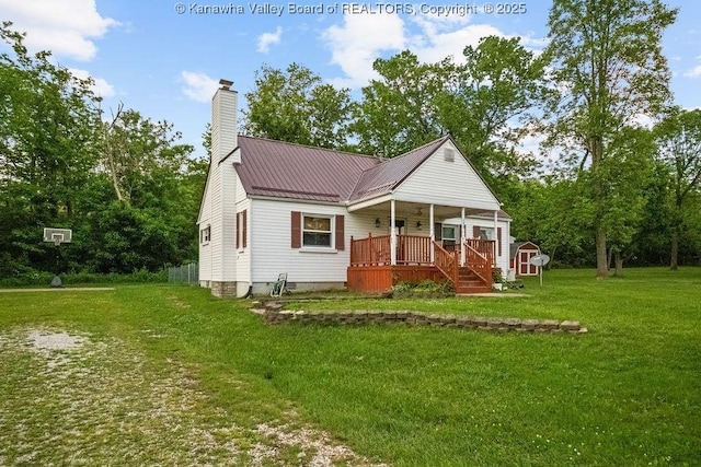 view of front of home featuring a front lawn, a chimney, a storage unit, an outdoor structure, and metal roof