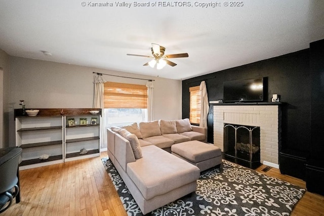living room featuring a ceiling fan, hardwood / wood-style flooring, and a fireplace