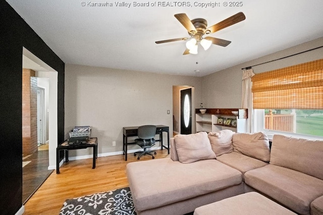 living area with light wood finished floors, a ceiling fan, and baseboards
