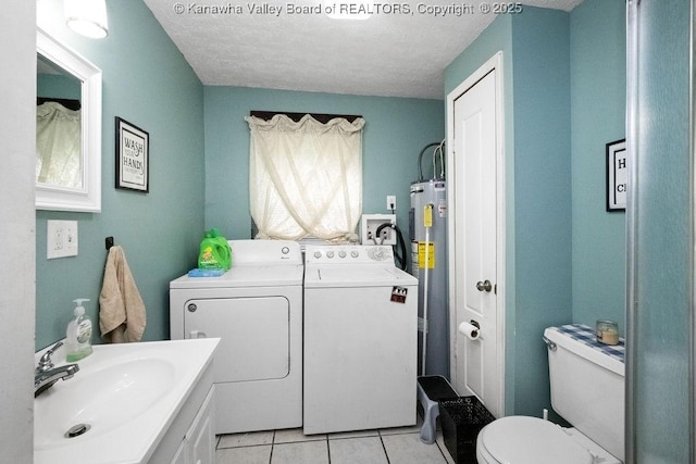 bathroom with separate washer and dryer, a sink, electric water heater, tile patterned flooring, and toilet