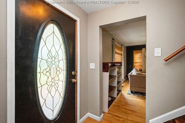 foyer with wood finished floors, baseboards, and stairway