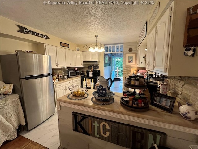 103 Chestnut Dr, Peytona, WV 25154 - kitchen featuring appliances with stainless steel finishes, a chandelier, white cabinets, a textured ceiling, and a peninsula