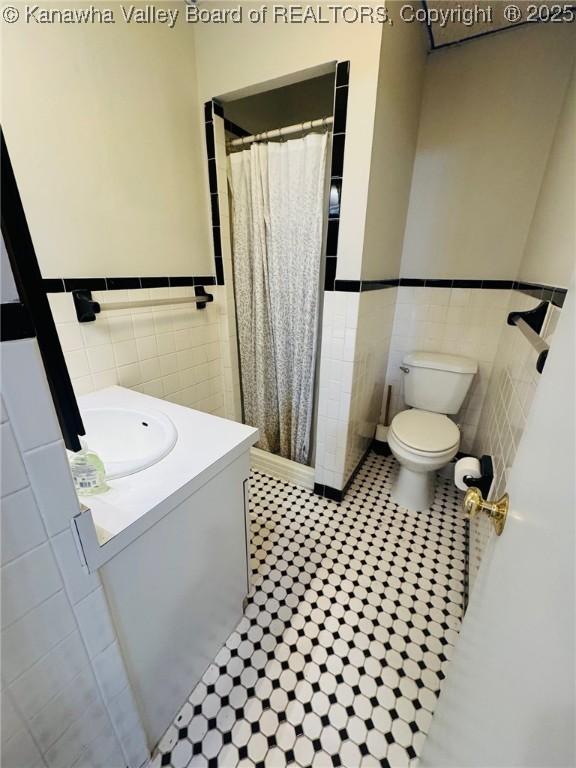 930 Mathews Ave, Charleston, WV 25302 - full bathroom featuring tile walls, a wainscoted wall, curtained shower, toilet, and vanity