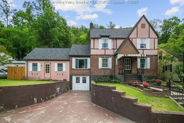 608 Kanawha Ave, Clendenin, WV 25045 - tudor-style house featuring stucco siding, a chimney, brick siding, roof with shingles, and concrete driveway