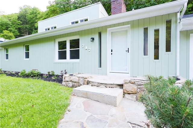 717 Chappell Rd, Charleston, WV 25304 - view of exterior entry with a chimney, a lawn, and board and batten siding