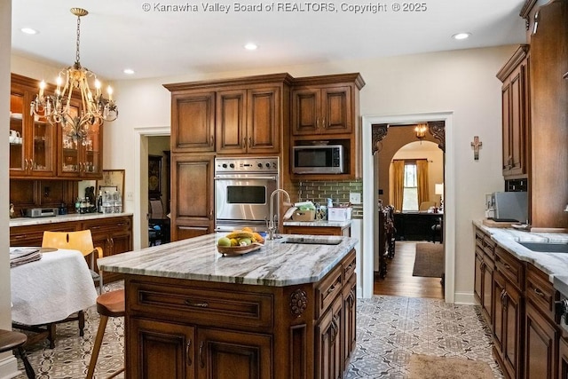 606 Fort Hill Dr, Charleston, WV 25314 - kitchen with appliances with stainless steel finishes, a sink, decorative backsplash, arched walkways, and hanging light fixtures