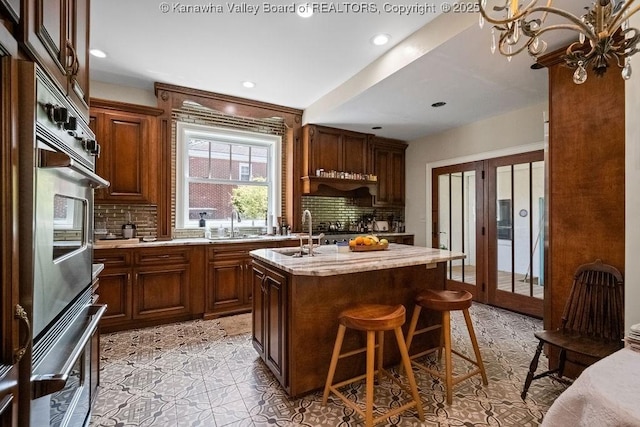 606 Fort Hill Dr, Charleston, WV 25314 - kitchen with decorative backsplash, a kitchen island with sink, a breakfast bar area, a sink, and recessed lighting