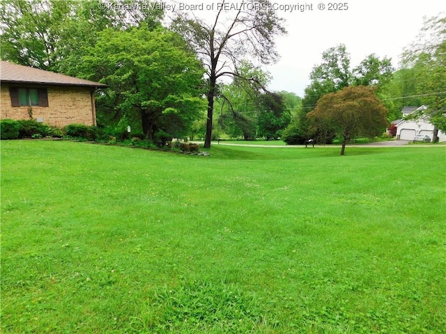 view of green lawn with view of wooded area