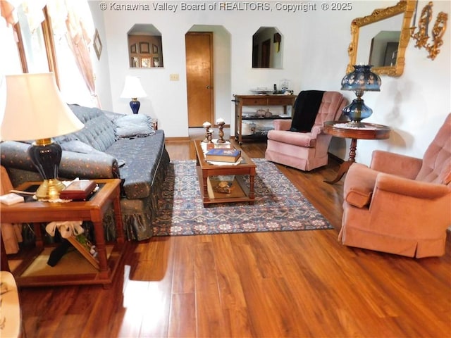 living area with wood finished floors and arched walkways