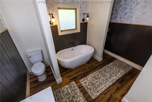352 Hidden Valley Rd, Chapmanville, WV 25508 - bathroom with wallpapered walls, wainscoting, wood finished floors, a freestanding tub, and toilet