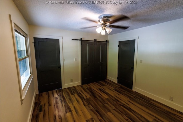 352 Hidden Valley Rd, Chapmanville, WV 25508 - unfurnished bedroom with dark wood-type flooring, a barn door, baseboards, a textured ceiling, and a ceiling fan