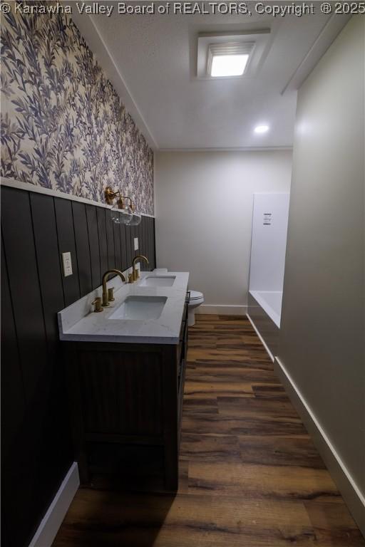 352 Hidden Valley Rd, Chapmanville, WV 25508 - bathroom featuring wood finished floors, wallpapered walls, toilet, baseboards, and double vanity