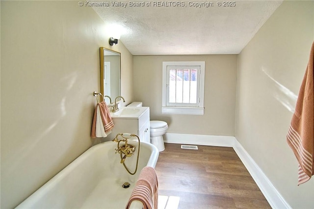 1505 Lee St E, Charleston, WV 25311 - full bath with a tub, toilet, a textured ceiling, wood finished floors, and baseboards