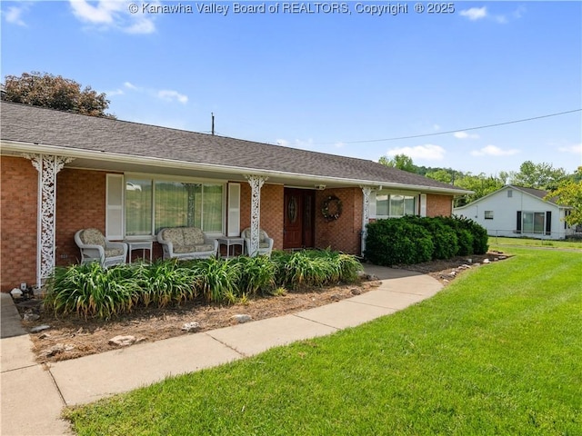 view of front facade with brick siding, covered porch, and a front yard