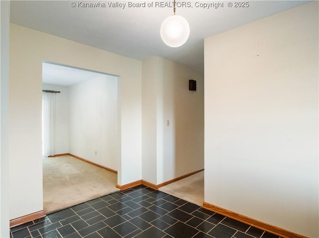 carpeted empty room featuring baseboards