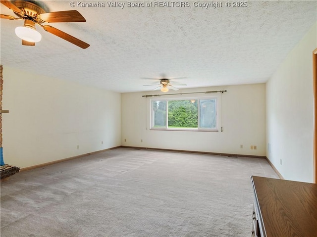 spare room with a ceiling fan, light colored carpet, a textured ceiling, and baseboards
