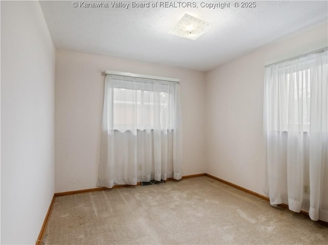 empty room with healthy amount of natural light, light carpet, and baseboards