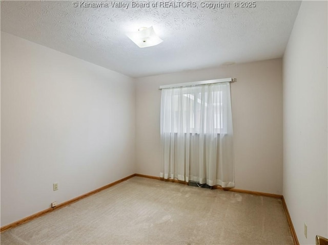 spare room featuring carpet flooring, baseboards, and a textured ceiling