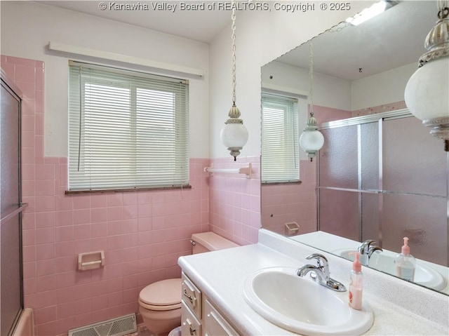 full bathroom featuring tile walls, plenty of natural light, a shower with shower door, toilet, and vanity