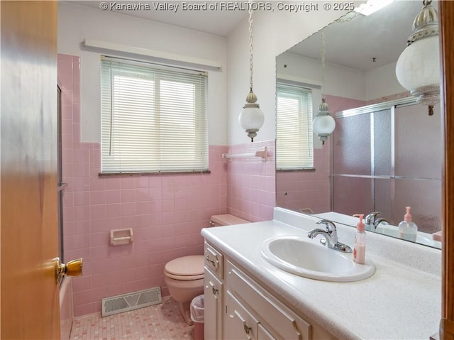 full bathroom featuring tile walls, a shower with shower door, tile patterned floors, vanity, and toilet