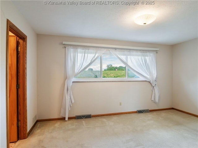 empty room featuring light carpet and baseboards