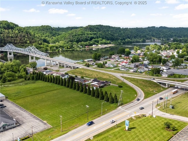 drone / aerial view of a nearby body of water, a forest, and a notable bridge