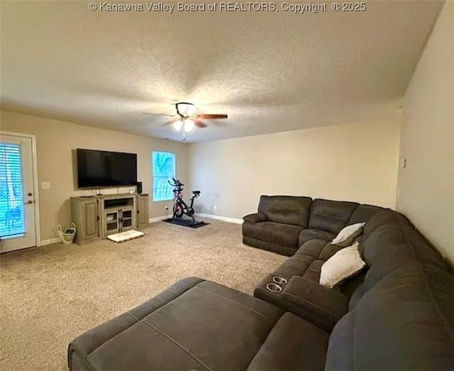 living room featuring ceiling fan, plenty of natural light, carpet flooring, a textured ceiling, and baseboards