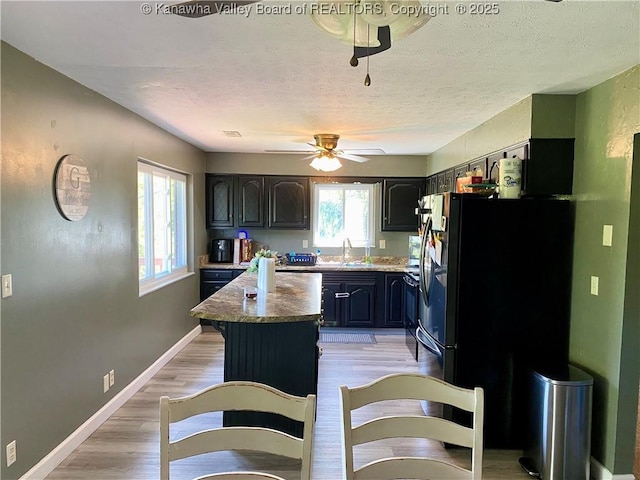 486 Woodland Acres Dr, Ripley, WV 25271 - kitchen with a ceiling fan, a kitchen island, a sink, a textured ceiling, and light wood-style floors