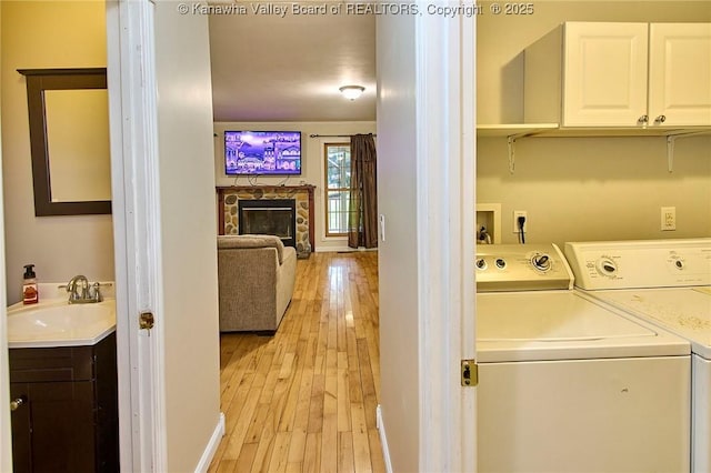 106 Coon Hollow Rd, Charleston, WV 25312 - washroom featuring washer and dryer, a sink, a high end fireplace, and light wood-type flooring