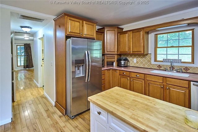 106 Coon Hollow Rd, Charleston, WV 25312 - kitchen featuring appliances with stainless steel finishes, a sink, brown cabinetry, decorative backsplash, and crown molding