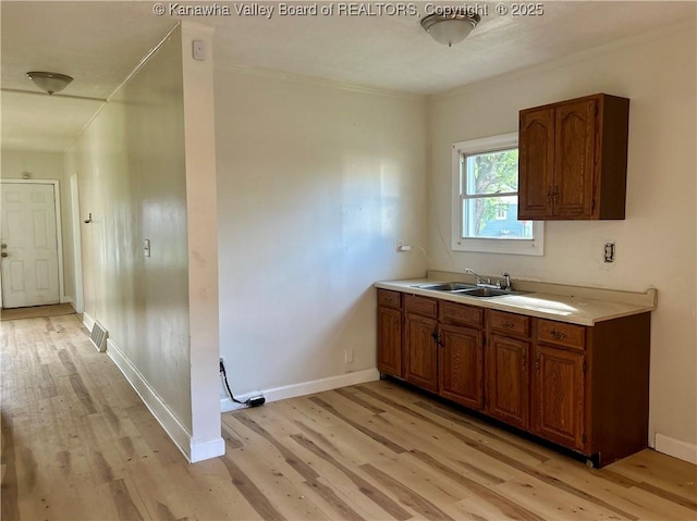 1005 E St, South Charleston, WV 25303 - kitchen with a sink, light wood-style flooring, light countertops, brown cabinetry, and ornamental molding
